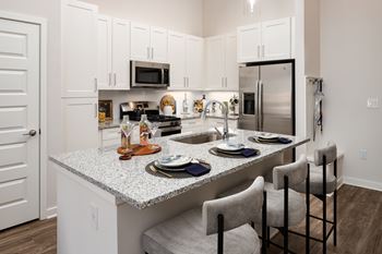 A kitchen with a granite countertop and white cabinets.